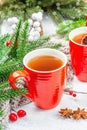 Hot winter or Christmas tea in ceramic red cups. Fir tree branches, lemon slice, spices and berries Royalty Free Stock Photo