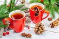 Hot winter or Christmas tea in ceramic red cups. Fir tree branches, lemon slice, spices and berries Royalty Free Stock Photo