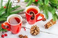 Hot winter or Christmas tea in ceramic red cups. Fir tree branches, lemon slice, spices and berries Royalty Free Stock Photo