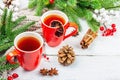 Hot winter or Christmas tea in ceramic red cups. Fir tree branches, lemon slice, spices and berries Royalty Free Stock Photo