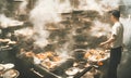 A hot wok with chef in a Chinese kitchen. back view of the chef, Chinese food being cooked in a wok on fire in the Chinese kitchen Royalty Free Stock Photo