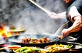 A hot wok with chef in a Chinese kitchen. back view of the chef, Chinese food being cooked in a wok on fire in the Chinese kitchen Royalty Free Stock Photo