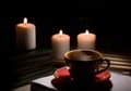 table with burning candles notebook pencil books, yellow mug with steam smoke