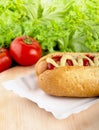 Hotdog with lettuce and tomatoes in the background on cutting bo