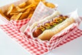 A hotdog topped with ketchup and mustard served with potato chips served in cardboard checkered trays.