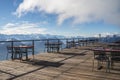 Hotel balcony with tables and chairs overlooking surrounding Alps and lakes on a cloudy day