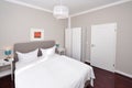 hotel bed bedroom - indoor interior, grey wall, white door, picture coloured, small night table Royalty Free Stock Photo