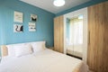 Hotel bedroom with blue walls, white curtains, pillowcases and sheets