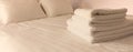 Hotel bedroom. White fluffy, folded towels, linen sheets and pillows on bed. Close up view. Royalty Free Stock Photo