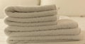 Hotel bedroom. White fluffy, folded towels, linen sheets and pillows on bed. Close up view. Royalty Free Stock Photo