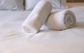 Hotel bedroom. White fluffy, rolled towels, linen sheets and pillows on a bed. Close up view Royalty Free Stock Photo