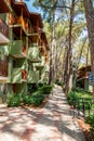 Hotel with green facade and wooden balconies overlooks paved walkway nestled among pines Royalty Free Stock Photo