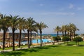 Hotel grounds with swimming pool, clear blue sea and trees, summer Sunny day palm trees Royalty Free Stock Photo