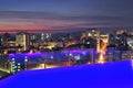 hotel pool, at sunset city and buildings with modern apartments and offices at night illumination a