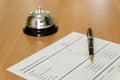 Hotel reservation form and luxury pen at reception concierge desk. With a bell ring for guest to call for a service, attention. Royalty Free Stock Photo