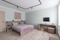 Hotel room with a large double bed in light colors