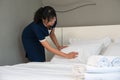 Hotel room service. Young Asian woman maid making bed in guest room Royalty Free Stock Photo