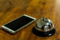 Hotel service call bell and smartphone on wooden reception front