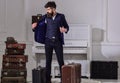 Hotel service concept. Man, traveller with beard and mustache with luggage, luxury white interior background. Macho