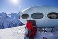 Hotel in the shape of an alien flying saucer standing high in the mountains among the snow capped mountain peaks. Dombay