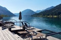 Hotel terrace with deck chairs on the shores of an alpine lake surrounded by mountains Royalty Free Stock Photo