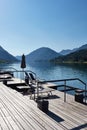 Hotel terrace with deck chairs on the shores of an alpine lake surrounded by mountains Royalty Free Stock Photo