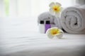 Hotel towel and shampoo and soap bath bottle set on white bed with plumeria flower decorated Royalty Free Stock Photo