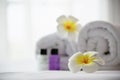 Hotel towel and shampoo and soap bath bottle set on white bed with plumeria flower decorated Royalty Free Stock Photo