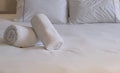 Hotel bedroom. White fluffy, rolled towels, linen sheets and pillows on a bed. Close up view Royalty Free Stock Photo