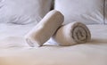 Hotel bedroom. White fluffy, rolled towels, linen sheets and pillows on a bed. Close up view Royalty Free Stock Photo