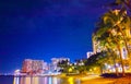 Hotel town and palm trees seen from Waikiki Beach at night Royalty Free Stock Photo