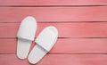 Hotel white slippers on a red wooden floor. Top view.