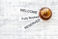 At the hotel. Words welcome, fully booked, reserved on light wooden table top view copyspace