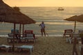 Hotel worker cleans the beach against the sea in the rays of the golden dawn