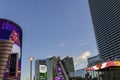 Hotels along a street with colorful digital billboards, lush green palm trees and blue sky with clouds in Nevada Las Vegas