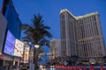 Hotels along a street with colorful digital billboards, lush green palm trees, people walking, cars driving on the street