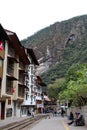 Hotels and restaurants lined along the train tracks with tourists and locals going about their day in Aguas Calientes, Peru