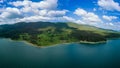 Hotels on shores of lake with reflection of mountains Rhodope against cloudy sky. Panorama, top view Royalty Free Stock Photo