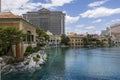 hotels , tower cranes and a Ferris wheel in the city skyline with a lake surrounded by lush green trees and people walking