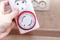 24 Hour 7 days a week mains plug in timer switch european socket for energy and money saving in the hand, blurred socket on