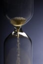 Hour Glass with running sand inside, on blue background. Time passing or countdown concept Royalty Free Stock Photo