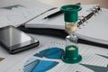 Hourglass on the background of the chart,pen, diary, phone. Royalty Free Stock Photo