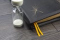 Hourglass and bible with dandelion seed. sow the seed of faith in God. Christianity and religion