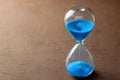 Hourglass with blue sand on brown background Royalty Free Stock Photo