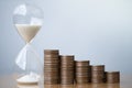 Hourglass blue sand and stack of coins. Royalty Free Stock Photo