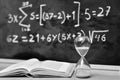 Hourglass and book on a table, with a blackboard background Royalty Free Stock Photo
