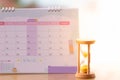 Hourglass on calendar concept for time slipping away for important appointment date.
