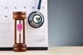 Hourglass, calendar and stestoscope over gently lit dark background template Royalty Free Stock Photo