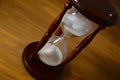 Hourglass, clock in front of wooden background with copy space. Closeup. Royalty Free Stock Photo