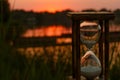 Hourglass counts down the time on the sunset pond Royalty Free Stock Photo